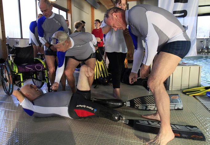 French athlete Philippe Croizon, whose arms and legs were amputated after an electric shock accident in March 1994, is helped by other divers in removing his equipment after diving in a 33 metre (36 yard) deep pool, the world's deepest pool built to train professional divers, at Nemo33 diving centre in Brussels January 10, 2013. Croizon, who swam with adapted prostheses that had flippers attached, broke a world record and became the first disabled person to dive to 33 metres, according to the organisers. REUTERS/Yves Herman (BELGIUM - Tags: SOCIETY SPORT DIVING) Published: Led. 10, 2013, 4:12 odp.