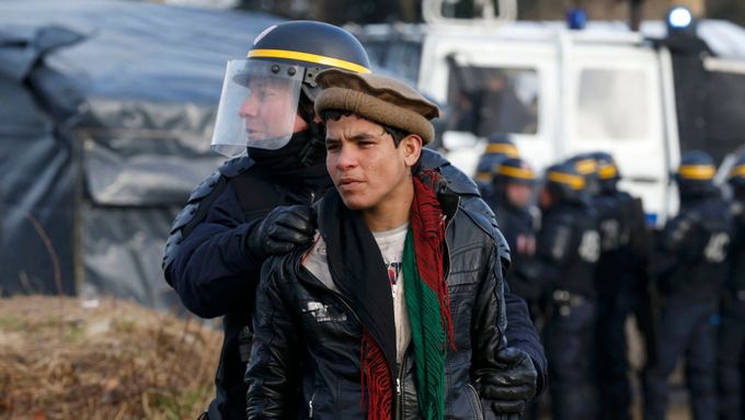 Francouzský policista odvádí Afghánce z tábora v Calais.