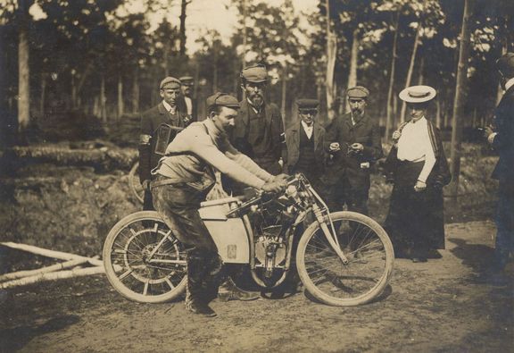 Mistři světa 1905! Klement (uprostřed) pózuje v Dourdanu se závodníkem Vondřichem, vezoucím si nářadí a díly na zádech.