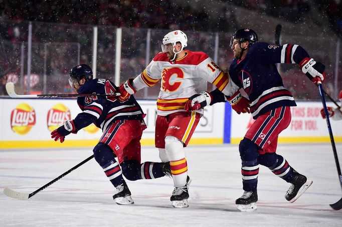 NHL 2019/2020, Heritage Classic, Calgary Flames - Winnipeg Jets: Tobias Rieder (16) skates through defenseman Josh Morrissey (44) and defenseman Tucker Poolman (3).