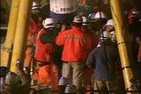 Střih. Záchranáři se shromažďují kolem speciální kapsle, která právě poprvé dorazila k povrchu země se zachráněným horníkem.