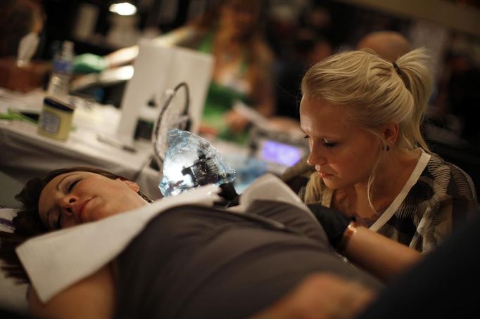 Shannon Toohey, 23, works on one of her clients during the National Tattoo Association Convention in Cincinnati, Ohio April 14, 2012. Toohey, who has been surrounded by tattoo artists during most of her young life, drew her first tattoo on her mother at the age of ten and now works at a tattoo shop on Long Island, New York. Picture taken April 14, 2012. REUTERS/Jason Reed (UNITED STATES - Tags: SOCIETY) ATTENTION EDITORS PICTURE 11 OF 31 FOR PACKAGE 'ADDICTED TO THE NEEDLE' TO FIND ALL PICTURES SEARCH 'ADDICTED NEEDLE' Published: Čer. 29, 2012, 12:59 odp.