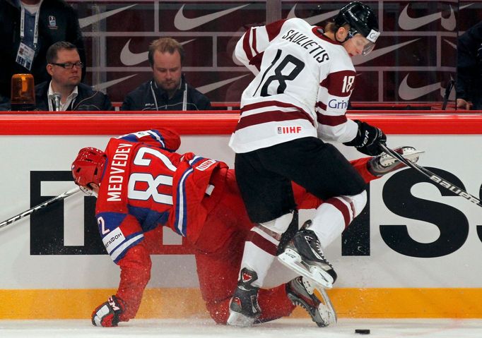 Jevgenij Medveděv a Kaspars Saulietis bojují u mantinelu v utkání MS v hokeji 2012 Rusko - Lotyšsko.