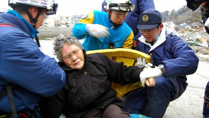 Záchranáři právě vynesli z trosek osmdesátiletou Sumi Abe. Spolu s jejím šestnáctiletým vnukem ji vytáhli z domu ve městě Išinomaki v prefektuře Mijagi.