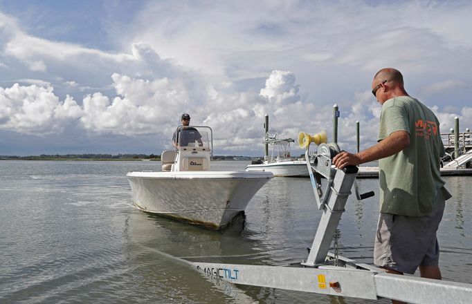 Nick Hobbs, left, and Randy Shaw, right, of Marine Warehouse Center, remove a customer's boat from the water in advance of Hurricane Florence in Wrightsville Beach, N.C.