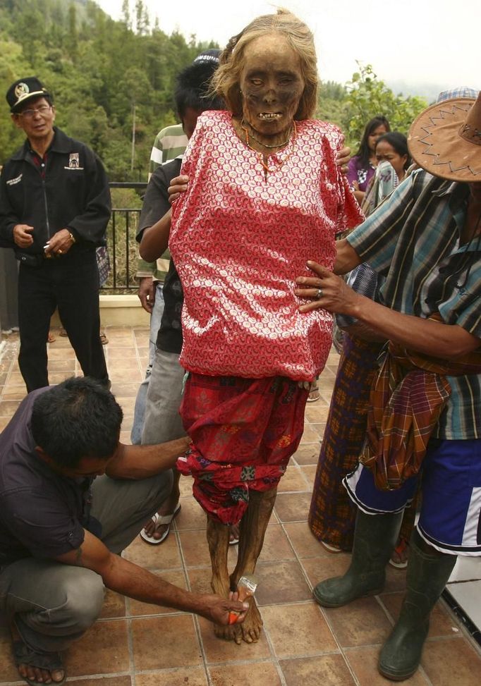 A family member cleans a mummy before giving it new clothes in a ritual in the Toraja district of Indonesia's South Sulawesi Province, August 23, 2012. The ritual, called Ma'nene, involves changing the clothes every three years of mummified ancestors to honor love for the deceased. Locals believe dead family members are still with them, even if they died hundreds of years ago, a family spokesman said. Picture taken August 23, 2012. REUTERS/Yusuf Ahmad (INDONESIA - Tags: SOCIETY RELIGION) Published: Srp. 24, 2012, 1:05 odp.