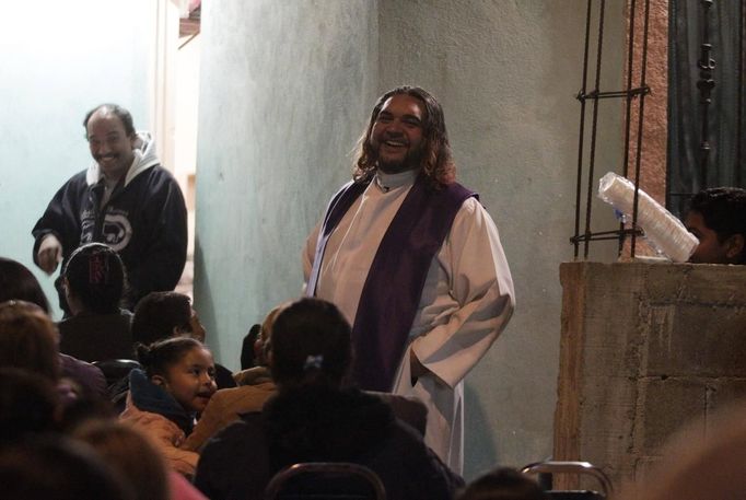 Catholic priest Adolfo Huerta (R), known as "Gofo", laughs while conducting a mass outside a house in a neighbourhood in Saltillo February 26, 2013. Ordained five years ago, Huerta is an unconventional priest who likes rock music, dyes the ends of his hair red, dresses in black, and enjoys riding his motorcycle. Huerta found God and priesthood while studying philosophy at the Pontifical University in Mexico City and working with HIV-positive patients and sex workers as a social activist. He says it is important to demystify faith and accept people's differences without judgment, and in his sermons he references rock songs, quotes books and tells jokes. Picture taken February 26, 2013. REUTERS/Daniel Becerril (MEXICO - Tags: RELIGION SOCIETY) ATTENTION EDITORS: PICTURE 15 OF 26 FOR PACKAGE 'CHURCH, FAITH AND ROCK'N ROLL' SEARCH 'PRIEST DANIEL' FOR ALL IMAGES Published: Bře. 15, 2013, 10:23 dop.