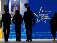 Momentka z Bruselu: Lidé kráčí kolem poutače, který láká k volbám do Evropského parlamentu. Plakát visí na Evropském parlamentu.