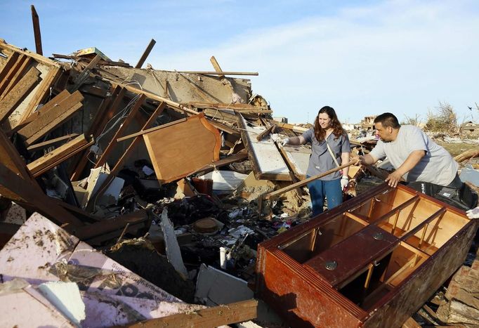 Greg Satterlee (R) shows his wife Genni where he thinks a file cabinet containing important papers may be in their tornado-destroyed home in Moore, Oklahoma May 21, 2013. Rescuers went building to building in search of victims and thousands of survivors were homeless on Tuesday after a massive tornado tore through the Oklahoma City suburb of Moore, wiping out whole blocks of homes and killing at least 24 people. REUTERS/Rick Wilking (UNITED STATES - Tags: DISASTER ENVIRONMENT) Published: Kvě. 22, 2013, 1:44 dop.