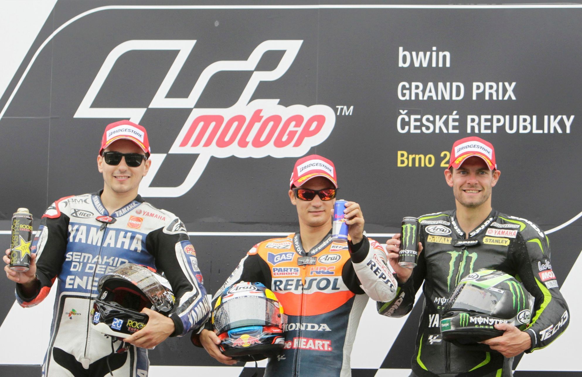 Španělští motocyklisté Dani Pedrosa (uprostřed) a Jorge Lorenzo (vlevo) slaví společně s Britem Calem Crutchlowem svá umístění ve Velké ceně České republiky 2012 v Brně.