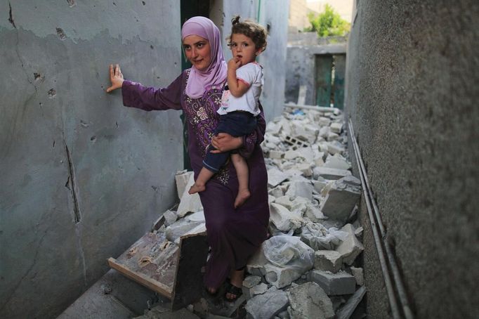 A woman carries her child while walking through the rubble in Attarib, on the outskirts of Aleppo province July 30, 2012. REUTERS/Zohra Bensemra (SYRIA - Tags: POLITICS CONFLICT CIVIL UNREST) Published: Čec. 30, 2012, 7:21 odp.