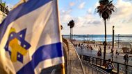 Izrael, Tel Aviv: izraelská vlajka se žlutou stužkou vlaje na promenádě u pláže ve městě.