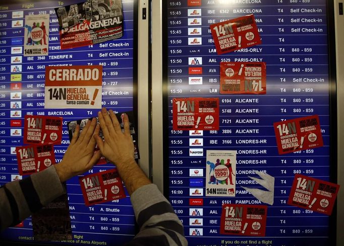 A union picketer pastes a sticker on a screen showing the departure flights at Terminal 4 during a 24-hour nationwide general strike in Madrid's Barajas airport November 14, 2012. Spanish and Portuguese workers are staging the first coordinated general strike across the Iberian Peninsula on Wednesday, shutting transport, grounding flights and closing schools to protest against spending cuts and tax hikes. REUTERS/Sergio Perez (SPAIN - Tags: POLITICS BUSINESS EMPLOYMENT CIVIL UNREST TRANSPORT) Published: Lis. 14, 2012, 9:05 dop.