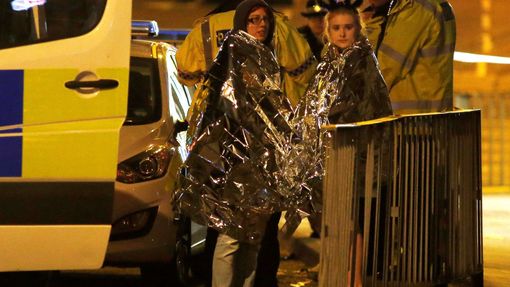 Dívky s termodekami a policiste před halou v Manchesteru.