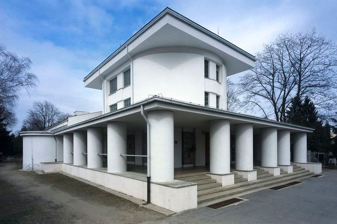 Krychle, válce, kremace Městské krematorium Nymburk, Lipová 563/20 (okres Nymburk) Bedřich Feuerstein, Bohumil Sláma, 1922-1924  Kremační hnutí za pohřeb žehem jako moderní technické cesty na věčnost přivedlo nymburské radní v roce 1920 k vypsání veřejné soutěže na pohřební síň na novém občanském hřbitově v Drahelicích. Vyhrál ji sice místní stavitel Ing. Josef Pfeifer, ale architektonické dopracování bylo svěřeno mladému Bedřichu Feuersteinovi. V roce 1922 předložil model budovy s obřadní síní, kolumbáriem a kremační částí. Zvolil na svou dobu ultramoderní pojetí úsporného a čistého purismu. Základem stavby na půdorysu kříže jsou jednoduché stereometrické tvary válců a krychlí, definující složitý prostorový útvar s oválným středním sálem. Na realizaci projektu spolupracoval architekt Bohumil Sláma (pozdější autor budovy Českého rozhlasu v Praze), v jehož ateliéru Feuerstein dříve praktikoval (1916-1917).