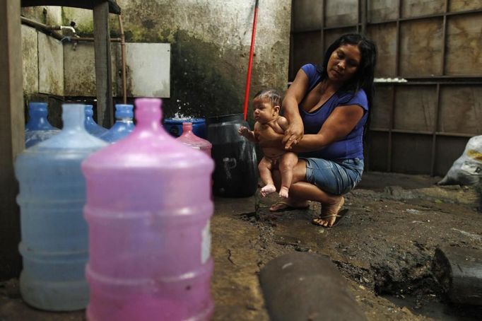 A native Indian woman bathes a baby at the Brazilian Indian Museum in Rio de Janeiro March 21, 2013. A native Indian community of around 30 individuals have been living in the abandoned Indian Museum since 2006. They have expired a deadline given by a court last Friday to leave the museum within 3 days, local media reported. The group is fighting against the destruction of the museum, which is next to the Maracana Stadium. REUTERS/Pilar Olivares (BRAZIL - Tags: POLITICS SPORT SOCCER) Published: Bře. 21, 2013, 11:52 dop.