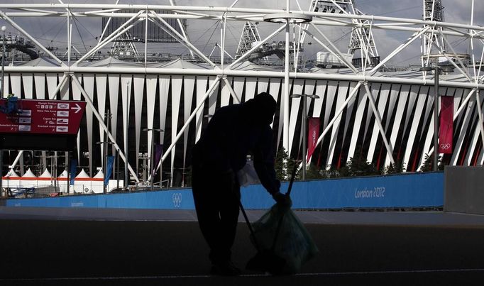 A cleaner sweeps the ground in front of the Olympic Stadium in the Olympic Park, in Stratford, east London, July 19, 2012. The 2012 London Olympic Games will begin in just over a week. REUTERS/Andrew Winning (BRITAIN - Tags: SPORT OLYMPICS) Published: Čec. 19, 2012, 8:59 dop.