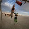 Gwen Barker and Rezwan Khan play on a swing art installation during the Burning Man 2014 &quot;Caravansary&quot; arts and music festival in the Black Rock Desert of Nevada