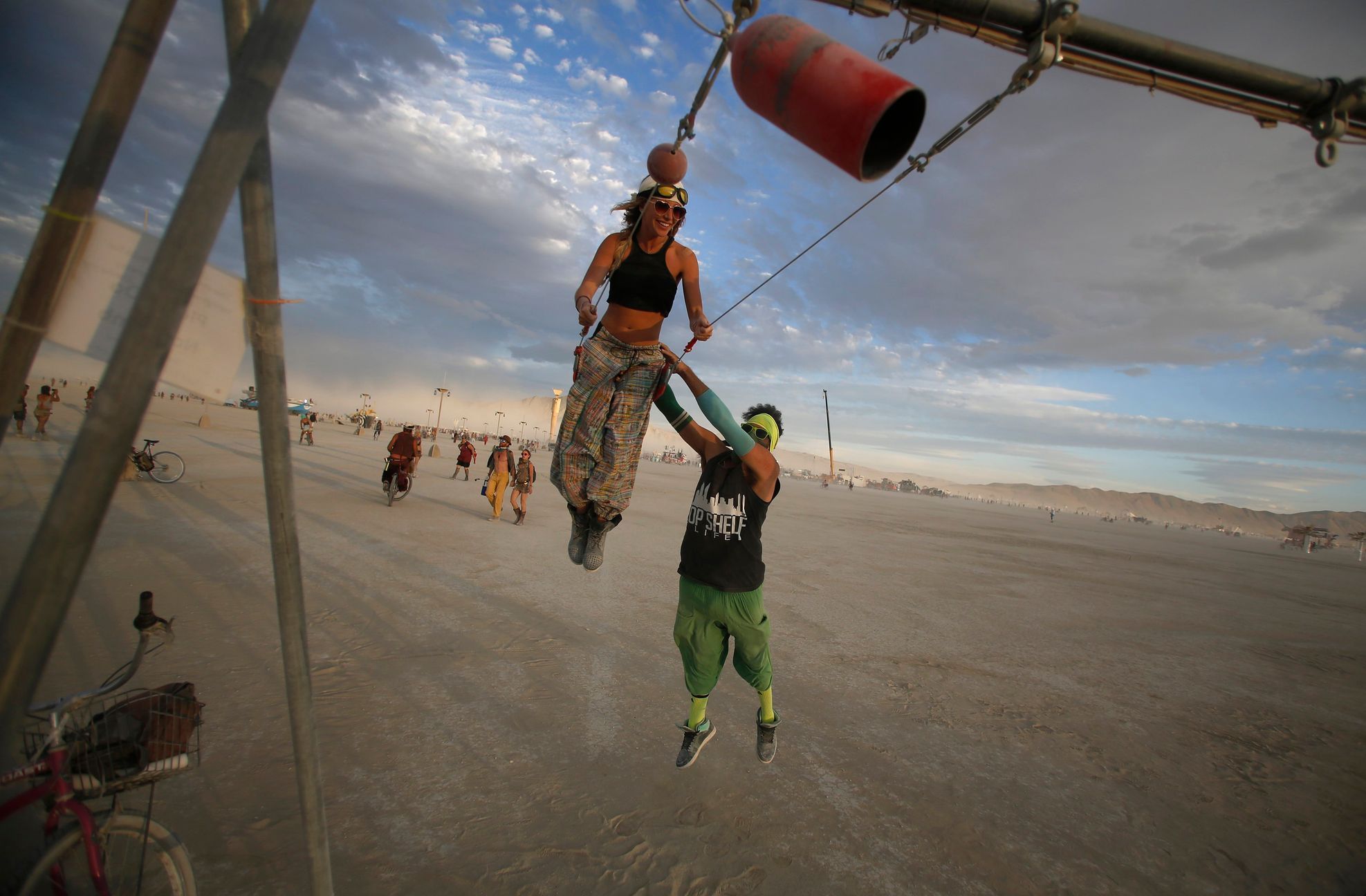 Gwen Barker and Rezwan Khan play on a swing art installation during the Burning Man 2014 &quot;Caravansary&quot; arts and music festival in the Black Rock Desert of Nevada
