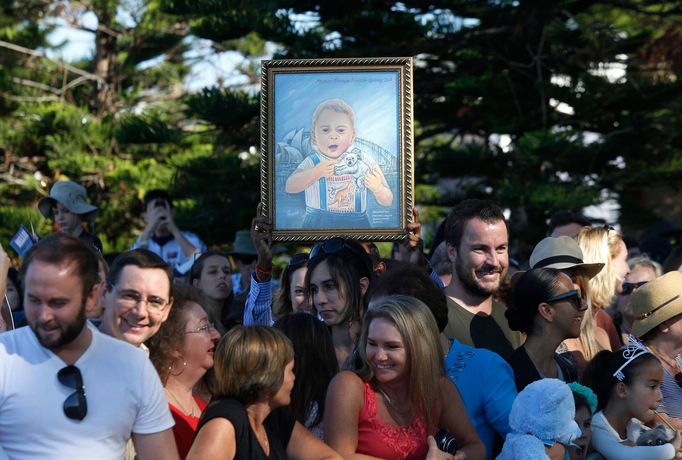 A supporter of Britain's Prince William and his wife Catherine, the Duchess of Cambridge, holds up a framed painting of their son Prince George at Sydney's Manly beach