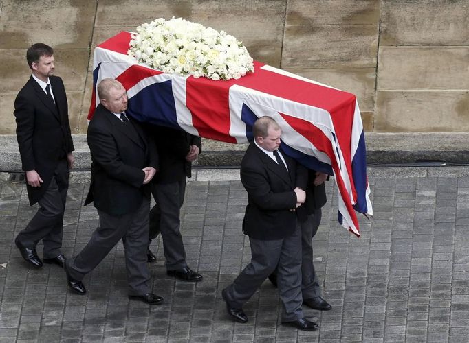 Vynášení rakve s ostatky Železné lady z Westminsterského paláce. Zakrátko bude tato rakev naložena na pohřební vůz a ten ji zaveze do Katedrály Svatého Pavla, kde se uskuteční pietní akt.