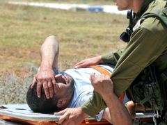 Izraelský voják eskortuje jednoho ze zraněných aktivistů do nemocnice