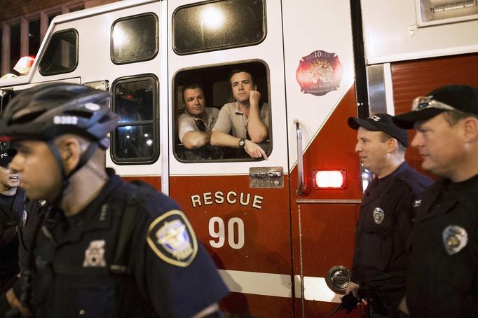 Police officers and firefighters watch as protesters march outside the site of the Democratic National Convention in Charlotte, North Carolina, September 4, 2012. REUTERS/Philip Scott Andrews (UNITED STATES - Tags: CIVIL UNREST POLITICS ELECTIONS CRIME LAW) Published: Zář. 5, 2012, 4:37 dop.