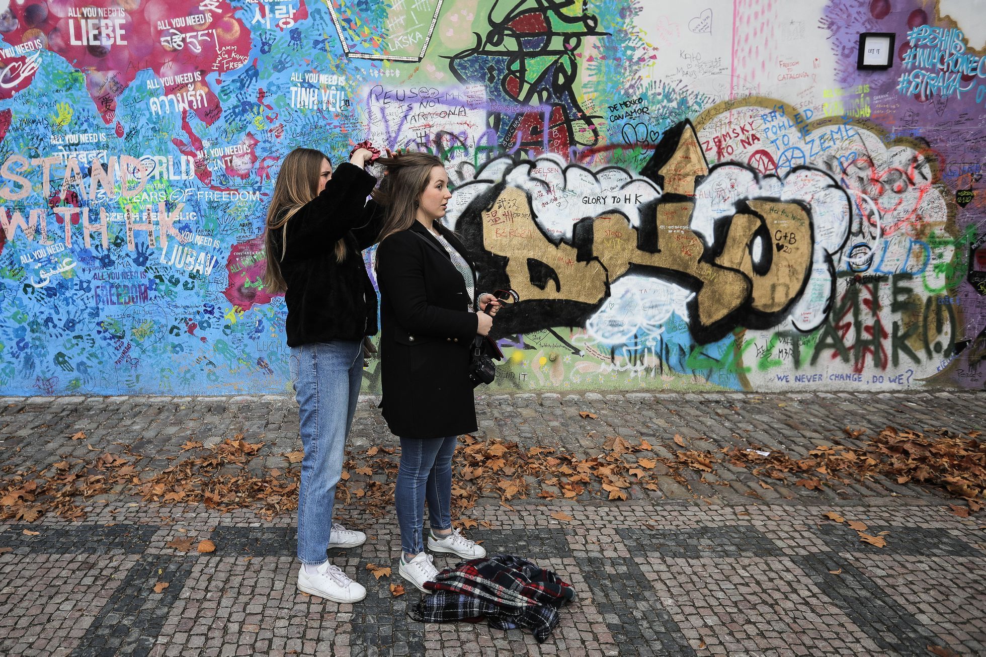 Lennonova zeď po třech měsících od malování - turisté, graffiti