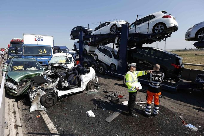 A police officer and a rescue worker talk amongst the wreckage of some of the 100 vehicles involved in multiple collisions, which took place in dense fog during the morning rush hour, on the Sheppey Bridge in Kent, east of London, September 5, 2013. Eight people were seriously injured and dozens hurt in the multiple crashes.