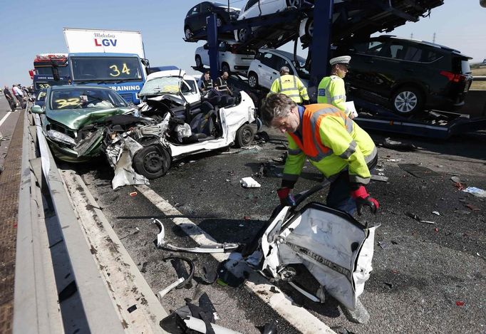 A rescue worker works amongst the wreckage of some of the 100 vehicles involved in multiple collisions, which took place in dense fog during the morning rush hour, on the Sheppey Bridge in Kent, east of London, September 5, 2013. Eight people were seriously injured and dozens hurt in the multiple crashes.