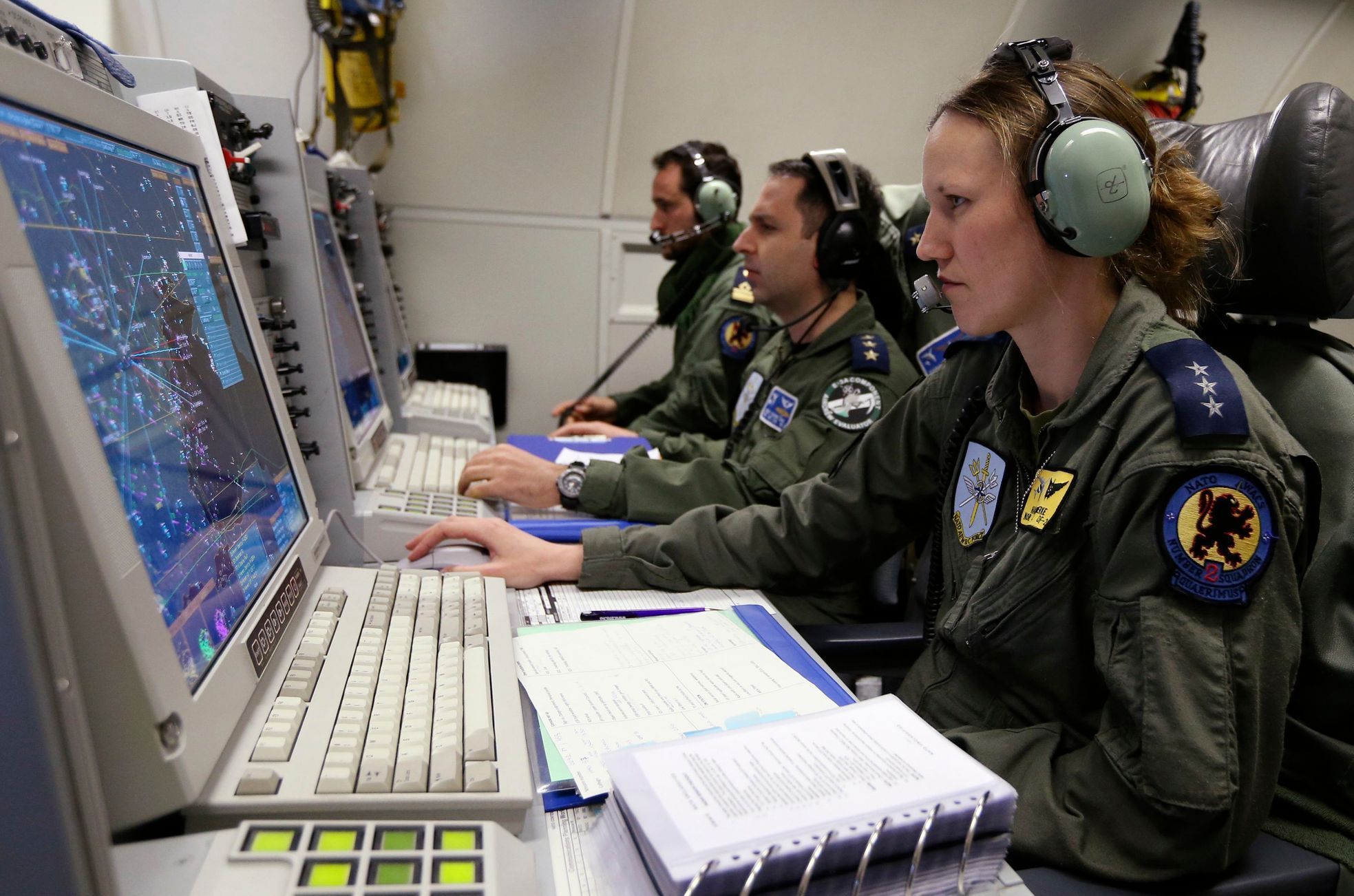 Controllers sit at screens aboard NATO AWACS aircraft during a surveillance flight over Romania