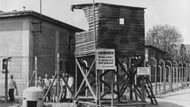 Toto je snímek z května 1945: Strážní věž tábora se skupinkou osvobozených vězňů.