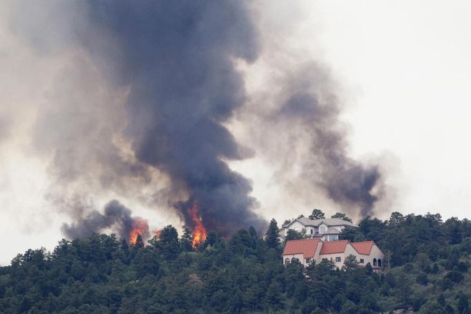 Flames explode next to houses in a mountain subdivision, in the Waldo Creek fire west of Colorado Springs June 24, 2012. A fast-growing wildfire has forced thousands of residents from homes in Colorado Springs, Colorado, and nearby communities as firefighters struggled on Sunday to contain out-of-control and wind-stoked blazes in several western U.S. States. REUTERS/Rick Wilking (UNITED STATES - Tags: DISASTER ENVIRONMENT) Published: Čer. 24, 2012, 9:30 odp.