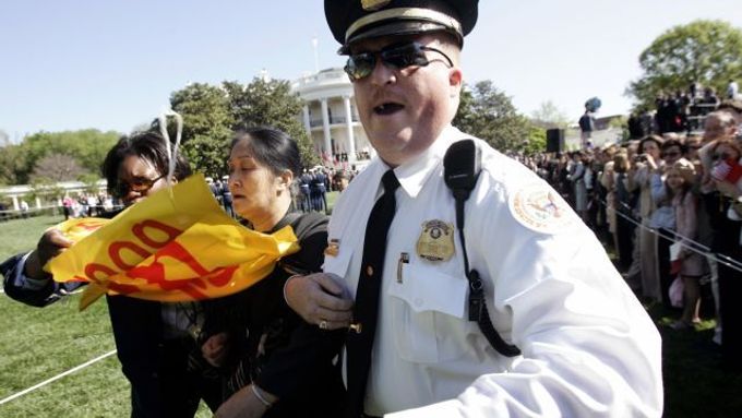 Ostraha Bílého domu odvádí protestující ženu.