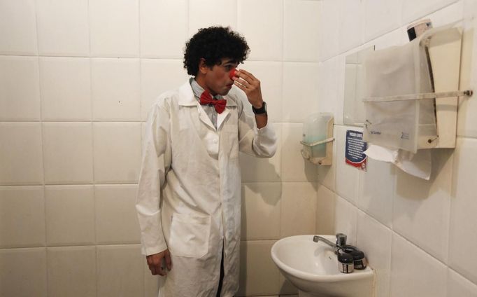 A member of the group Traffic Psychologists fixes his clown nose in a toilet of a petrol station in preparation for his performance at a traffic light in Sao Paulo July 23, 2012. Traffic Psychologists is a non-profit non-governmental organization which aims to humanize traffic and reduce the level of stress caused to drivers. Sao Paulo has more than 7 million vehicles, according to figures from the state transport authority Detran. Picture taken July 23, 2012. REUTERS/Nacho Doce (BRAZIL - Tags: TRANSPORT SOCIETY) Published: Čec. 24, 2012, 6:48 dop.