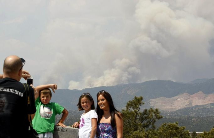 Michael and Isabella (C) Smaldino pose with Rinata Dominguez (R) as the city of Colorado Springs (backgound), Colorado is seen in the path of the Waldo Canyon wildfire burning in the mountains west of the city, June 24, 2012. Firefighters in western U.S. states struggled to contain out-of-control wind-stoked wildfires across the U.S. west as summer temperatures mounted, and a fresh blaze consumed more homes in Colorado. The Smaldino children's parents were fighting the fire. REUTERS/Rick Wilking (UNITED STATES - Tags: DISASTER ENVIRONMENT) Published: Čer. 24, 2012, 5:50 odp.