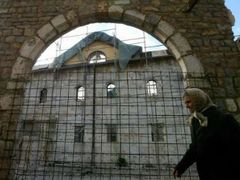 Albánská žena prochází kolem zničeného pravoslavného kostela v Prizrenu, pocházejícího ze 14.století.