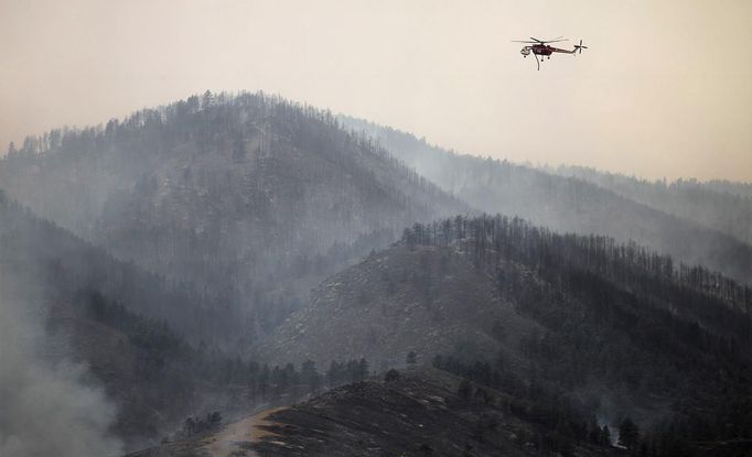 A firefighting helicopter surveys the eastern front of the High Park fire for hot spots, near Laporte, Colorado June 10, 2012. A wind-driven wildfire burning in a rugged Colorado canyon spread out of control, forcing hundreds of people to evacuate and one person in the fire zone was reported missing, officials said on Sunday. REUTERS/Marc Piscotty (UNITED STATES - Tags: DISASTER ENVIRONMENT) Published: Čer. 10, 2012, 9:33 odp.