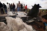 Lidé se dívají na to, co z letounu, který spadl nedaleko Benghání, zbylo.