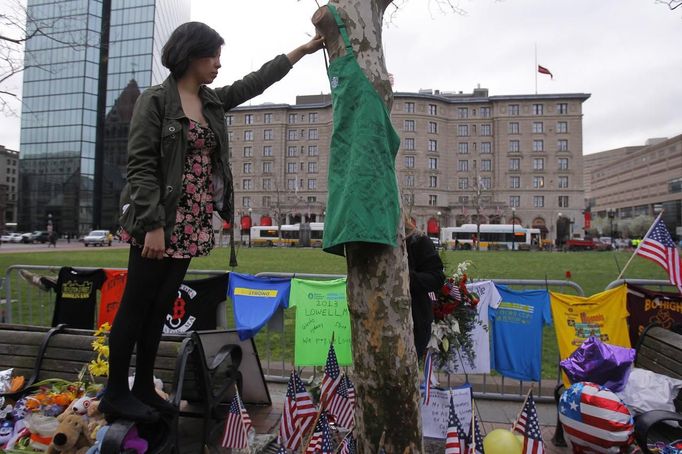 Priscilla Portugal, an employee of the Starbucks store on Boylston Street located near the site of the second explosion, hangs an apron on a tree inside a memorial set up in memory of the victims of the Boston Marathon bombings after the street reopened to the public for the first time since the bombings in Boston, Massachusetts April 24, 2013. REUTERS/Jessica Rinaldi (UNITED STATES - Tags: CRIME LAW CIVIL UNREST) Published: Dub. 24, 2013, 1:43 odp.