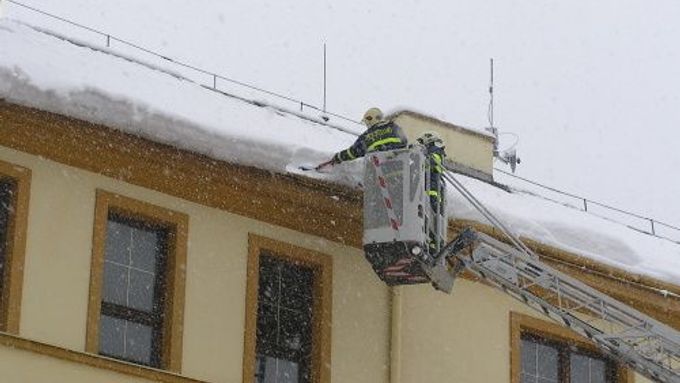 Hasiči ostraňují sníh ze střechy.