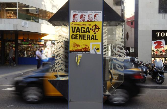 A car drives past a poster calling for a general strike in Las Ramblas, central Barcelona November 12, 2012. Spain's two largest labour unions had called a general strike for November 14, the second against the conservative government since they took power in December and coinciding with industrial action in Portugal on the same day. The poster in Catalan reads, "Necessary General Strike". REUTERS/Gustau Nacarino (SPAIN - Tags: POLITICS CIVIL UNREST BUSINESS TRANSPORT) Published: Lis. 12, 2012, 5:52 odp.