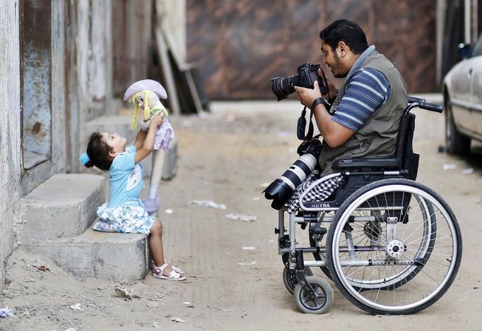 Wheelchair-bound Palestinian freelance photographer Moamen Qreiqea takes pictures of his daughter outside his home in Gaza City October 1, 2012. Qreiqea, 25, lost both his legs in an Israeli air strike in 2008 while taking pictures east of Gaza. The father of two is determined to continue his career despite his disability. REUTERS/Suhaib Salem (GAZA - Tags: MEDIA SOCIETY) Published: Říj. 1, 2012, 3:39 odp.