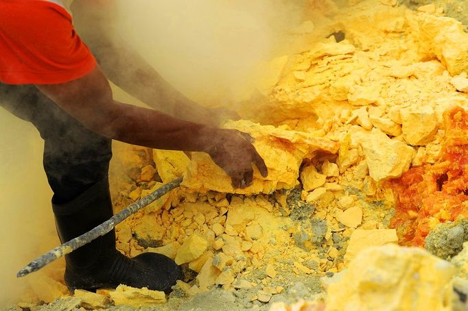 This photo taken on December 25, 2010 shows an Indonesian miner extracting blocks of sulphur with his bare hands from the bottom of the crater of Indonesia's active Kajah Iwen volcano, in the extreme east of Java island. Some 350 sulphur miners eke out a dangerous and exhausting living on the active volcano, carrying hauls of up to 80 kilos of "yellow gold" which will be bought by local factories and used to refine sugar or make matches and medicines. The miners extract the liquid sulphur as it flows out of hot iron pipes. Once in the open air, it cools, crystallises and turns bright yellow. The sulphur is then loaded into wicker baskets at either end of bamboo yokes and carried back over the lip of the crater and down the side of the volcano, a treacherous journey of four kilometres (2.5 miles).