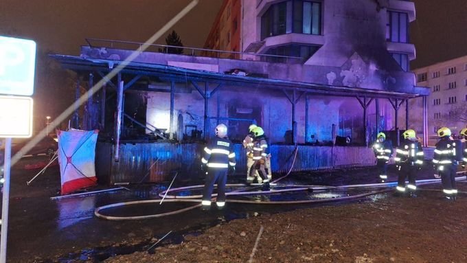 Na fotce ze sobotní noci je dobře vidět ohořelá dřevěná konstrukce baru, kde postupně podle svědků došlo ke třem explozím. Zbytky pergoly hasiči zdemolovali v neděli večer.