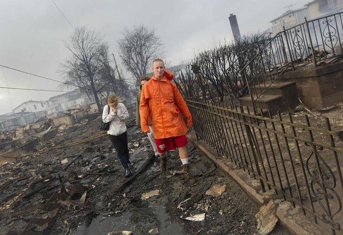 Keith Klein and Eileen Blair (L) walk among homes devastated by fire and the effects of Hurricane Sandy at the Breezy Point section of the Queens borough in New York October 30, 2012. Millions of people across the eastern United States awoke on Tuesday to scenes of destruction wrought by monster storm Sandy, which knocked out power to huge swathes of the nation's most densely populated region, swamped New York's subway system and submerged streets in Manhattan's financial district. REUTERS/Shannon Stapleton (UNITED STATES - Tags: DISASTER ENVIRONMENT) Published: Říj. 30, 2012, 1:45 odp.