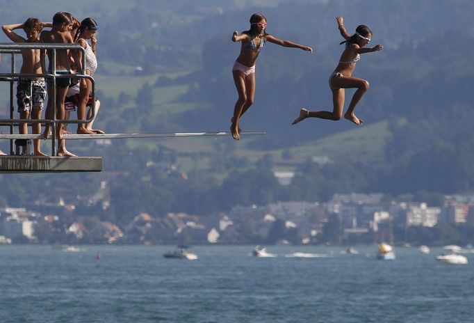 Teenagers jump into Lake Zurich on a hot sunny summer day in Kuesnacht, August 19, 2012. The Federal Office of Meteorology MeteoSwiss has launched a warning for a heat wave for the weekend until Wednesday August 22. REUTERS/Christian Hartmann (SWITZERLAND - Tags: ENVIRONMENT SOCIETY) Published: Srp. 19, 2012, 3:46 odp.