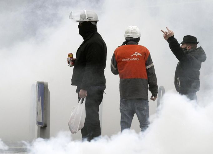 Clouds of tear gas surround Arcelor Mittal employees who gesture at French riot police during a demonstration next to the European Parliament in Strasbourg, February 6, 2013. ArcelorMittal, the world's largest steel producer, plans to shut a coke plant and six finishing lines at its site in Liege, Belgium, affecting 1,300 employees. REUTERS/Jean Marc Loos (FRANCE - Tags: POLITICS) Published: Úno. 6, 2013, 4:58 odp.