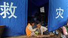 Children have instant noodles under a rescue tent after Saturday's earthquake hit Lushan county, Ya'an, Sichuan province, April 22, 2013. Hundreds of survivors of an earthquake that killed nearly 200 people in southwest China pushed into traffic on a main road on Monday, waving protest signs, demanding help and shouting at police. The Chinese characters on the tent read "Disaster relief". Picture taken April 22, 2013. REUTERS/Stringer (CHINA - Tags: DISASTER SOCIETY) Published: Dub. 23, 2013, 3:05 dop.