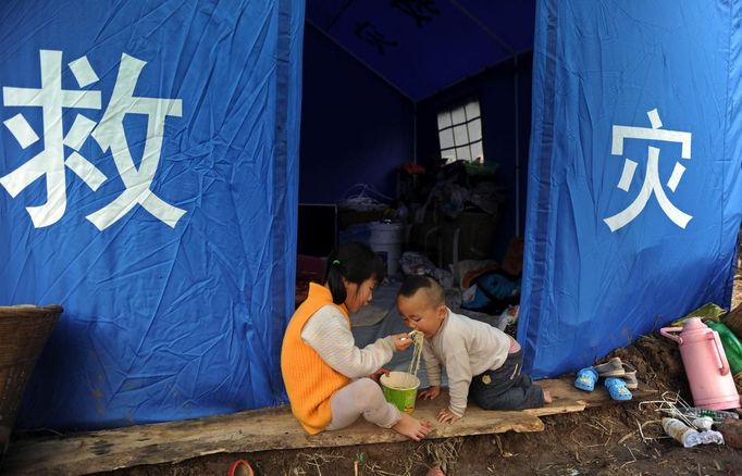 Children have instant noodles under a rescue tent after Saturday's earthquake hit Lushan county, Ya'an, Sichuan province, April 22, 2013. Hundreds of survivors of an earthquake that killed nearly 200 people in southwest China pushed into traffic on a main road on Monday, waving protest signs, demanding help and shouting at police. The Chinese characters on the tent read "Disaster relief". Picture taken April 22, 2013. REUTERS/Stringer (CHINA - Tags: DISASTER SOCIETY) Published: Dub. 23, 2013, 3:05 dop.